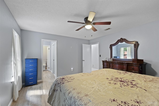 bedroom featuring baseboards, a textured ceiling, visible vents, and light wood-style floors