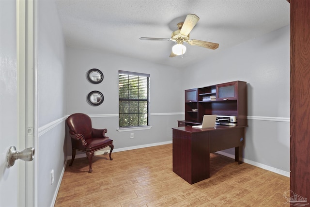 office area with a textured ceiling, light wood finished floors, baseboards, and a ceiling fan