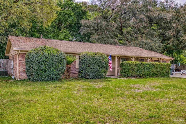 ranch-style house featuring fence, a front lawn, and central AC unit