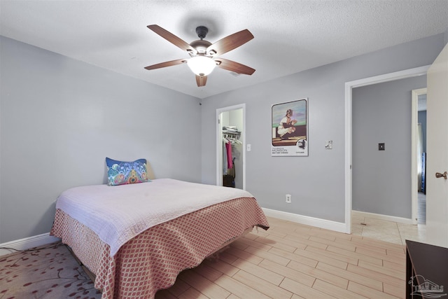 bedroom with light wood-style flooring, baseboards, a spacious closet, and ceiling fan