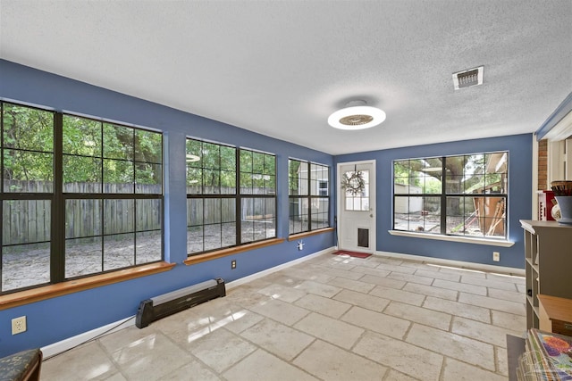 interior space with a textured ceiling, visible vents, and baseboards