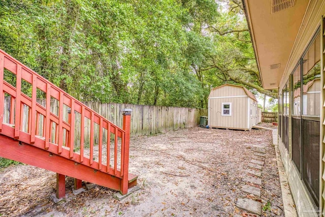 view of yard featuring a fenced backyard, an outbuilding, visible vents, and a shed