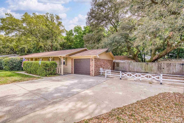 view of front facade featuring fence, concrete driveway, brick siding, and a garage
