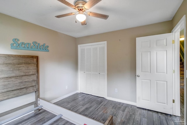 unfurnished bedroom with dark wood-type flooring, a closet, and ceiling fan