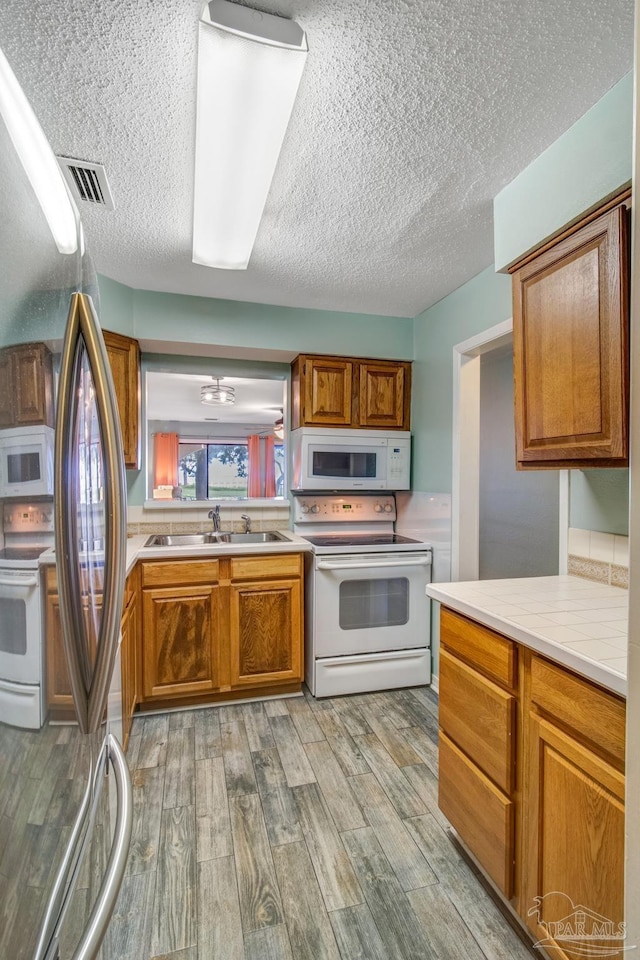 kitchen featuring white appliances, light hardwood / wood-style floors, and sink