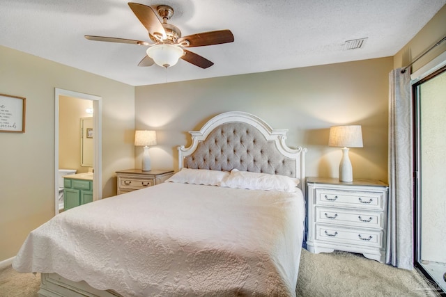 carpeted bedroom featuring ceiling fan, connected bathroom, and a textured ceiling