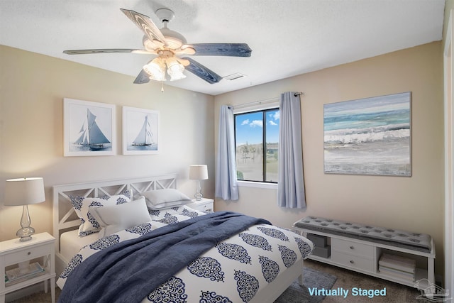 bedroom featuring ceiling fan, dark carpet, and a textured ceiling