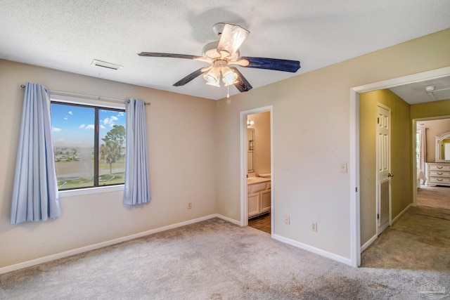 unfurnished bedroom featuring a textured ceiling, light colored carpet, ceiling fan, and ensuite bathroom