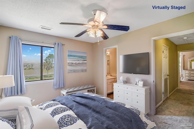 bedroom featuring ceiling fan, connected bathroom, light colored carpet, and a textured ceiling