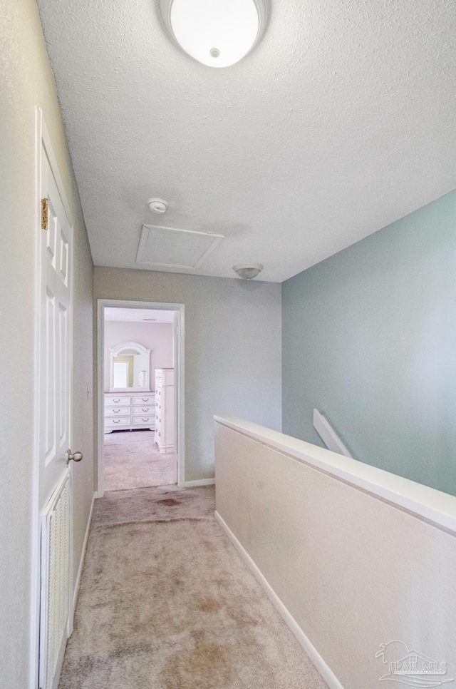 hall featuring light carpet and a textured ceiling