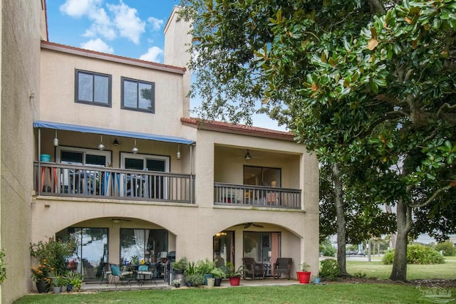 back of property featuring ceiling fan, a patio area, and a balcony