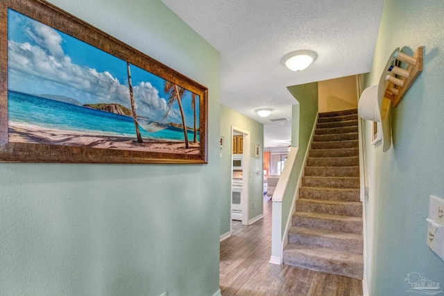 stairs featuring hardwood / wood-style floors and a textured ceiling