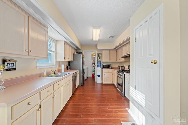 kitchen with sink, stainless steel appliances, a textured ceiling, light wood-type flooring, and light brown cabinets