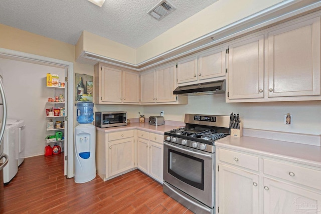 kitchen with appliances with stainless steel finishes, washing machine and clothes dryer, a textured ceiling, and light hardwood / wood-style flooring