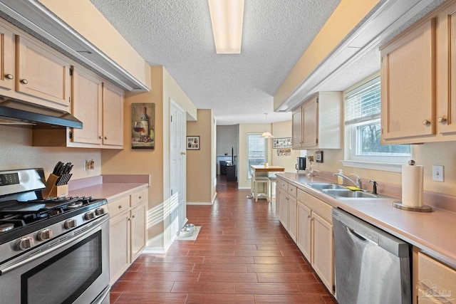 kitchen with sink, light brown cabinets, appliances with stainless steel finishes, dark hardwood / wood-style floors, and pendant lighting