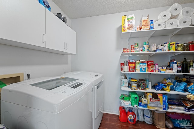 clothes washing area with cabinets, washing machine and clothes dryer, and a textured ceiling