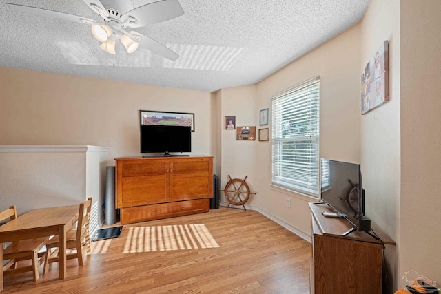 interior space with ceiling fan, a textured ceiling, and light wood-type flooring