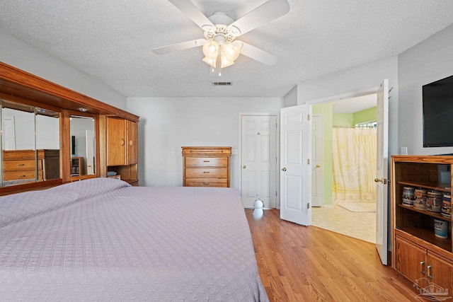 bedroom featuring connected bathroom, ceiling fan, light hardwood / wood-style flooring, and a textured ceiling