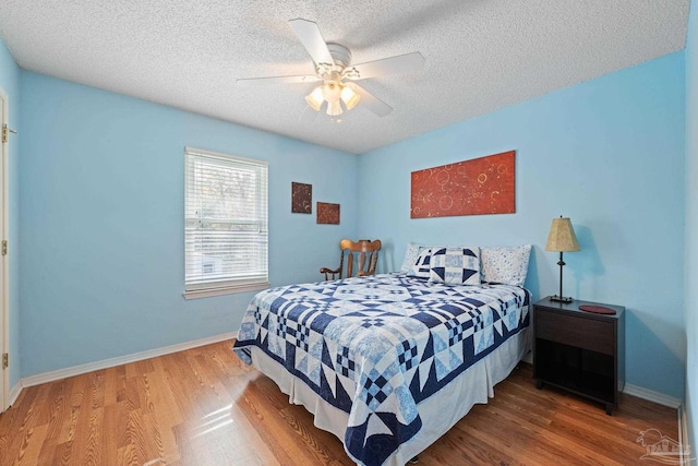 bedroom with ceiling fan, wood-type flooring, and a textured ceiling