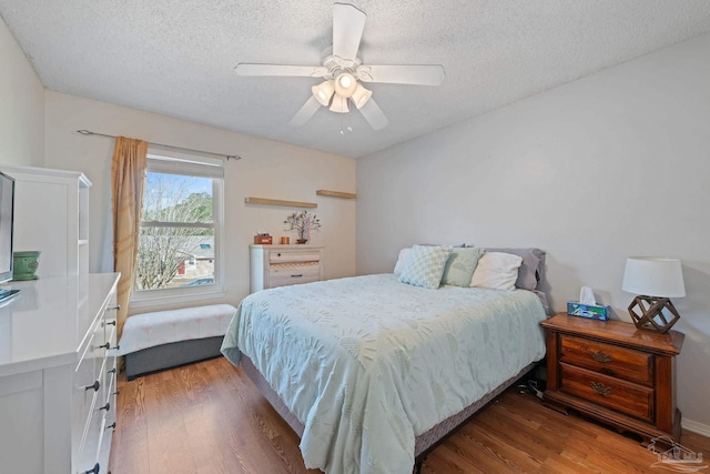 bedroom with ceiling fan, a textured ceiling, and dark hardwood / wood-style flooring