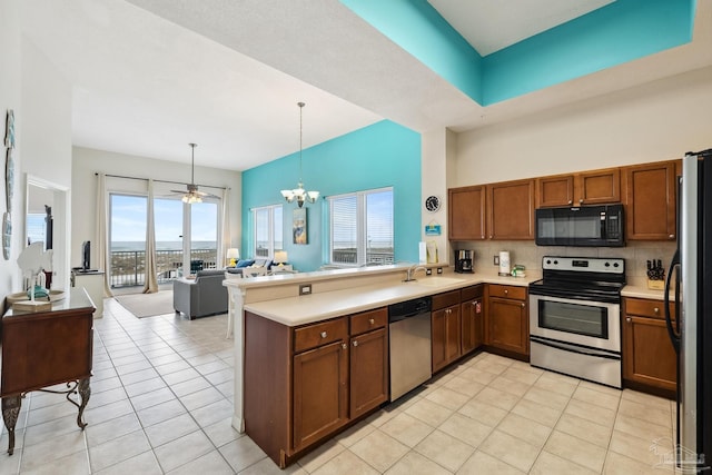 kitchen with appliances with stainless steel finishes, decorative light fixtures, backsplash, light tile patterned floors, and kitchen peninsula