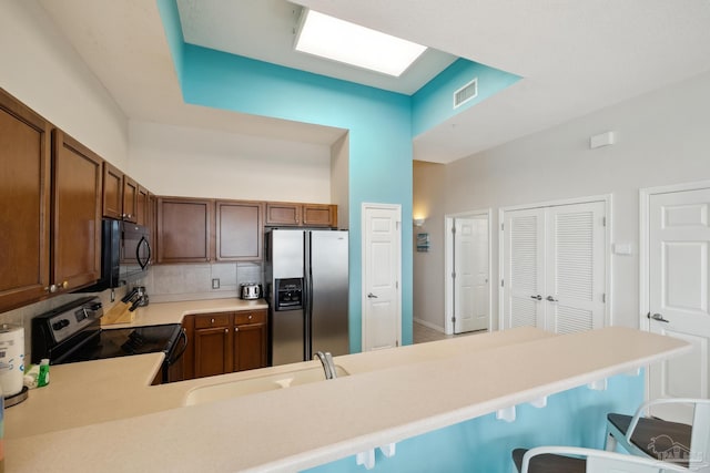 kitchen featuring a breakfast bar, tasteful backsplash, sink, kitchen peninsula, and stainless steel appliances