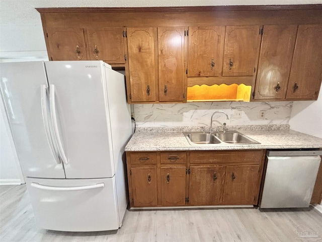 5737 Chumuckla Hwy, Pace, FL 32571 - kitchen with freestanding refrigerator, dishwasher, a sink, light wood-style flooring, and brown cabinetry