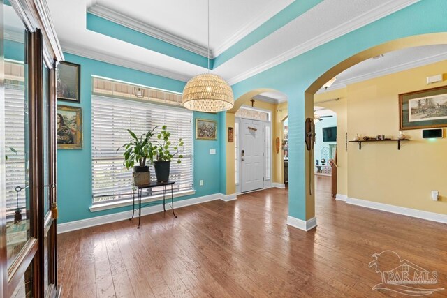 foyer with a tray ceiling, ornamental molding, hardwood / wood-style flooring, and a healthy amount of sunlight