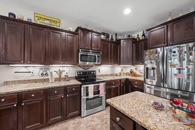 kitchen with light stone counters, appliances with stainless steel finishes, and dark brown cabinets