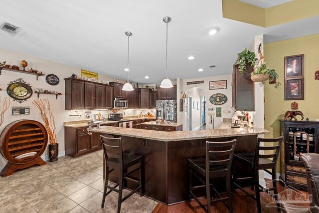 kitchen featuring a kitchen breakfast bar, decorative light fixtures, stainless steel appliances, and kitchen peninsula