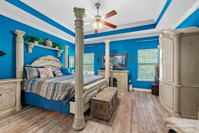 bedroom featuring crown molding, light hardwood / wood-style flooring, a tray ceiling, and ceiling fan