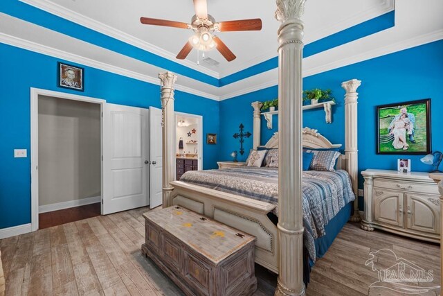 bedroom with ensuite bathroom, a tray ceiling, ceiling fan, hardwood / wood-style flooring, and ornamental molding