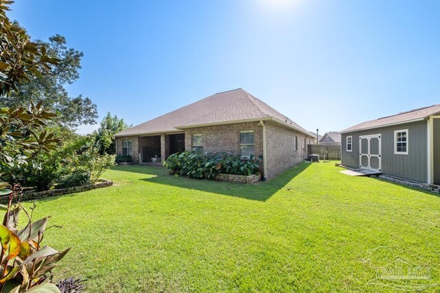 back of property with a yard, a storage unit, and central air condition unit