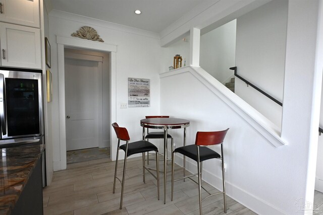 dining space featuring light wood-type flooring and ornamental molding