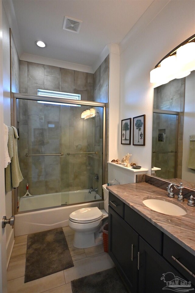 full bathroom featuring vanity, tile patterned floors, combined bath / shower with glass door, toilet, and ornamental molding