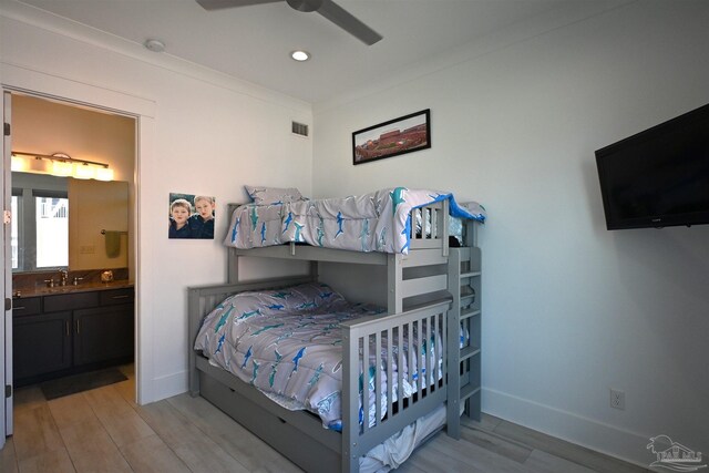 bedroom featuring ceiling fan, sink, ensuite bathroom, light hardwood / wood-style floors, and ornamental molding