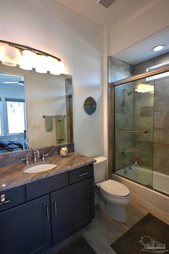 full bathroom with vanity, toilet, wood-type flooring, and bath / shower combo with glass door