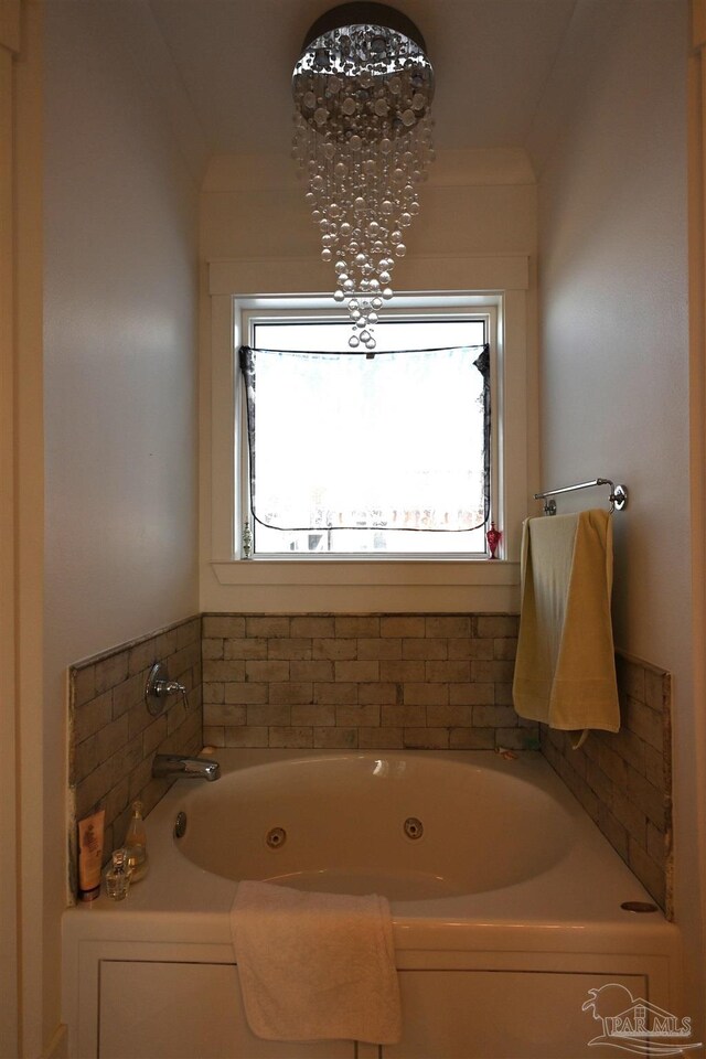 bathroom with a bathtub, crown molding, and an inviting chandelier