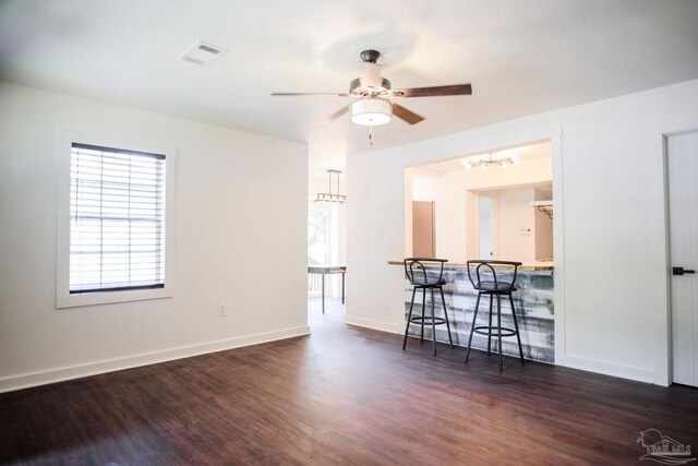 unfurnished room featuring dark wood-type flooring and ceiling fan with notable chandelier