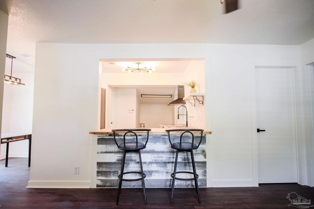 interior space featuring a breakfast bar, dark wood-type flooring, kitchen peninsula, and wall chimney exhaust hood