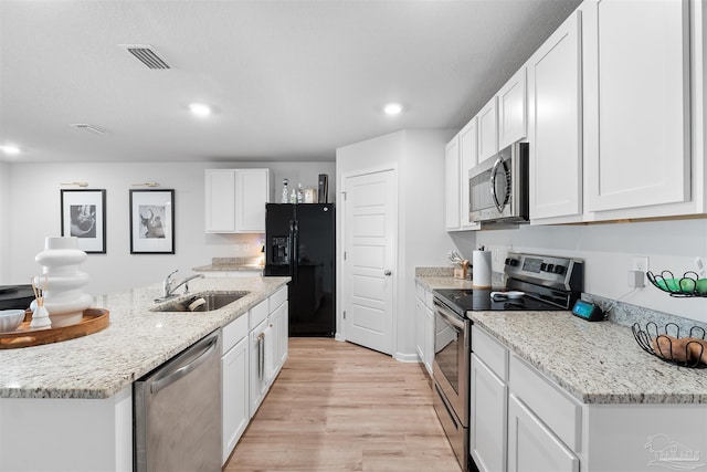 kitchen featuring light stone countertops, white cabinetry, sink, appliances with stainless steel finishes, and light wood-type flooring