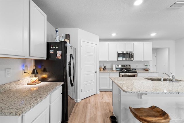 kitchen with light stone counters, white cabinetry, sink, and appliances with stainless steel finishes