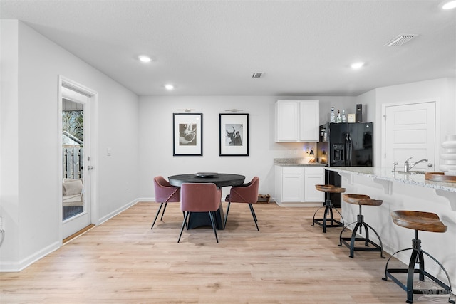 dining space with a textured ceiling, light wood-type flooring, and sink