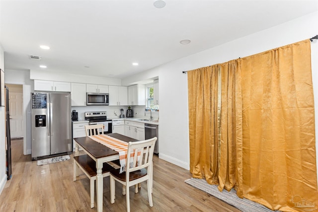 kitchen with sink, light hardwood / wood-style flooring, stainless steel appliances, and white cabinetry