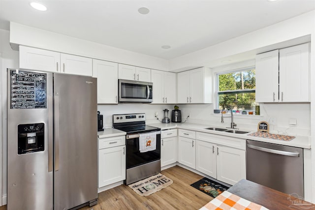 kitchen with white cabinetry, light hardwood / wood-style floors, appliances with stainless steel finishes, and sink