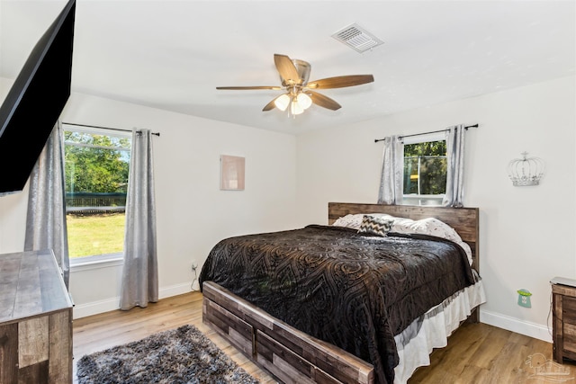 bedroom featuring light hardwood / wood-style flooring, multiple windows, and ceiling fan