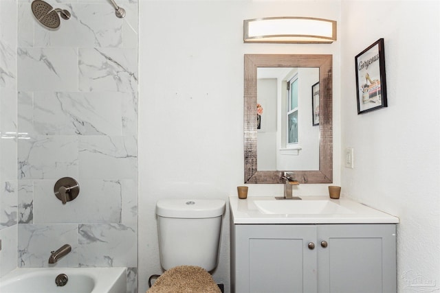 full bathroom featuring tiled shower / bath, vanity, and toilet