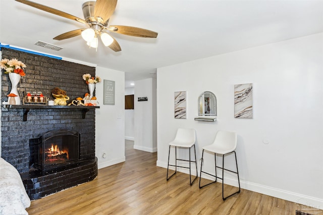 living room featuring light hardwood / wood-style floors, a fireplace, and ceiling fan