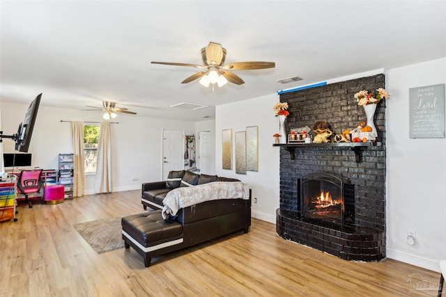 living room featuring a fireplace, light wood-type flooring, and ceiling fan