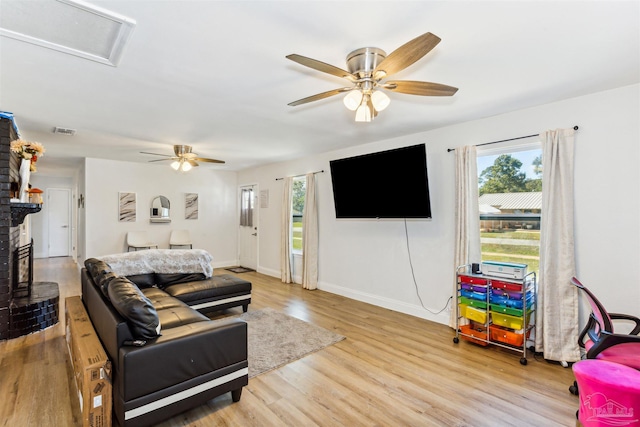 living room with light hardwood / wood-style flooring, a fireplace, and ceiling fan